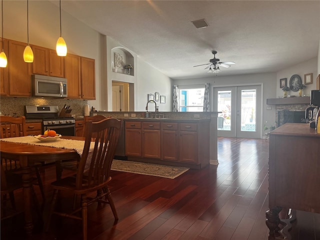 kitchen with backsplash, a peninsula, french doors, dark wood-style floors, and stainless steel appliances