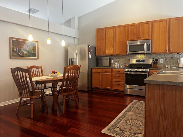 kitchen with visible vents, brown cabinets, a sink, tasteful backsplash, and stainless steel appliances