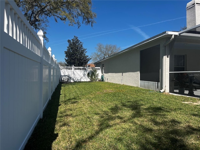 view of yard with glass enclosure and a fenced backyard