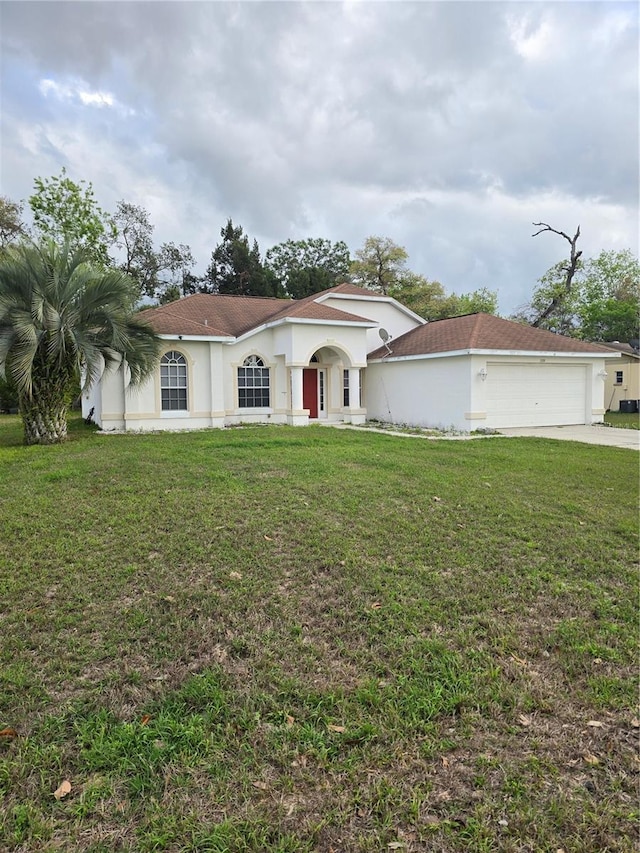 mediterranean / spanish home with a garage, stucco siding, and a front yard