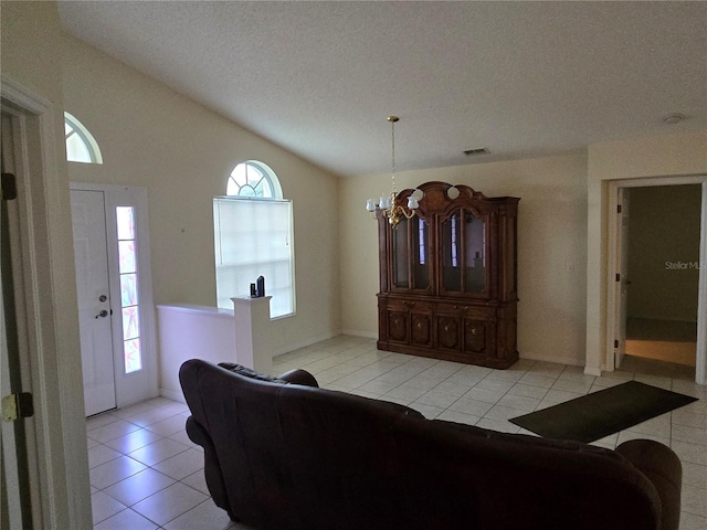 living area featuring an inviting chandelier, vaulted ceiling, light tile patterned floors, and visible vents