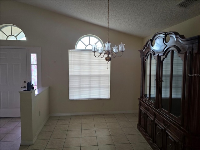 entrance foyer with visible vents, a textured ceiling, an inviting chandelier, light tile patterned floors, and lofted ceiling