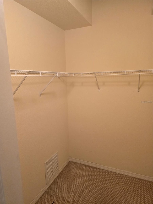 walk in closet featuring visible vents and light colored carpet