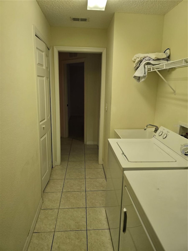 laundry area featuring laundry area, light tile patterned flooring, visible vents, and a textured ceiling