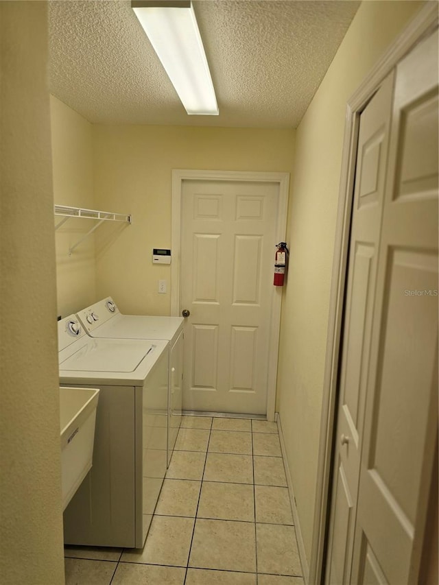 laundry room featuring washer and dryer, a sink, a textured ceiling, light tile patterned floors, and laundry area