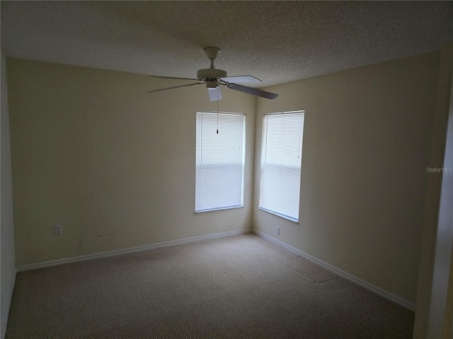 empty room with baseboards, light carpet, a textured ceiling, and a ceiling fan