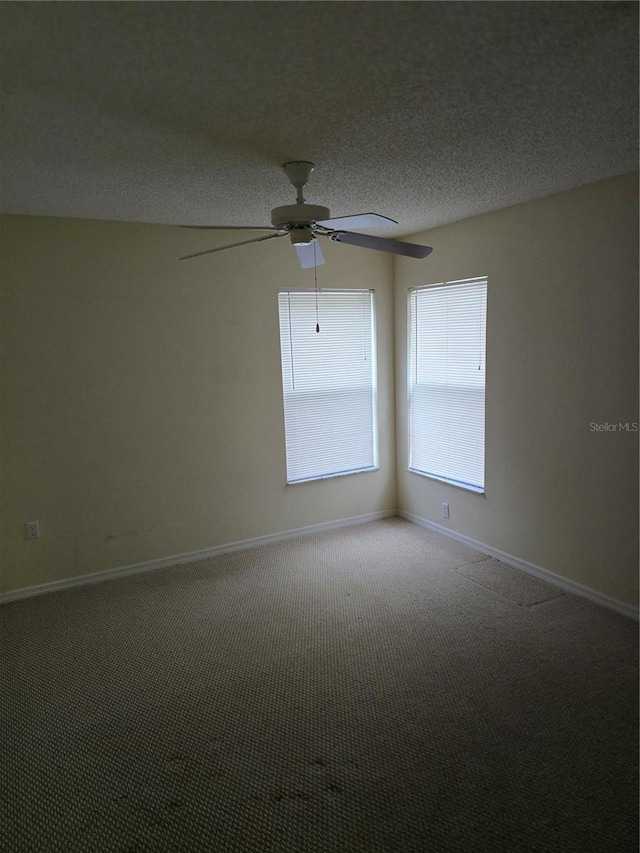 carpeted spare room featuring ceiling fan, a textured ceiling, and baseboards