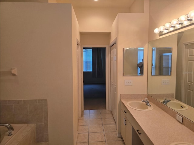 bathroom featuring tile patterned floors, a relaxing tiled tub, double vanity, and a sink