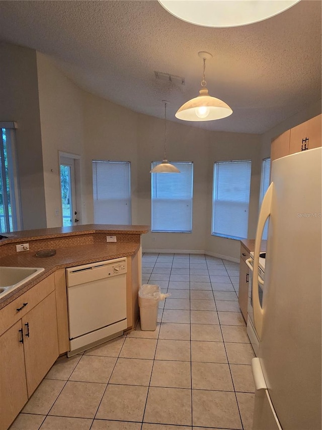 kitchen with decorative light fixtures, vaulted ceiling, light tile patterned flooring, white appliances, and a textured ceiling