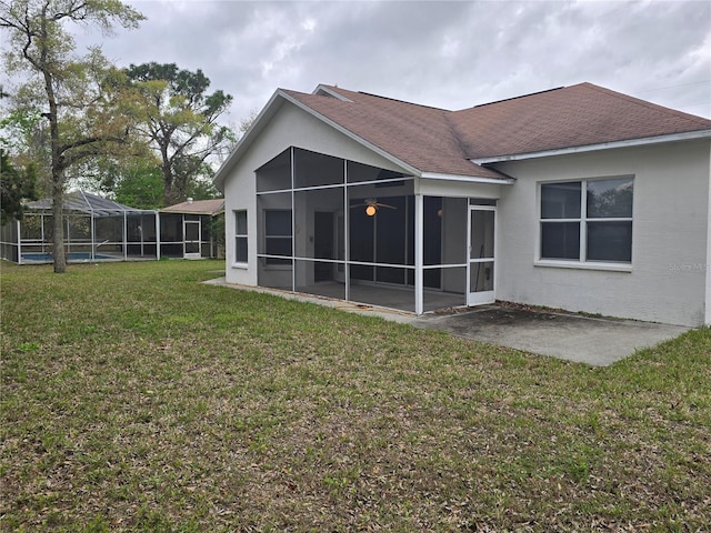 back of house with glass enclosure, a patio, a yard, and a shingled roof