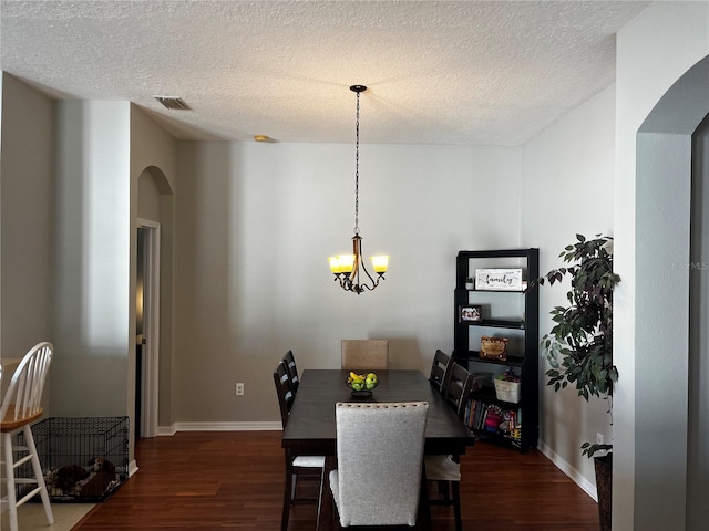 dining room with arched walkways, visible vents, dark wood finished floors, and a notable chandelier