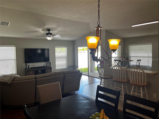 tiled dining room with lofted ceiling, a ceiling fan, visible vents, and a textured ceiling