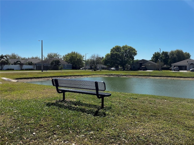 surrounding community with a water view and a lawn