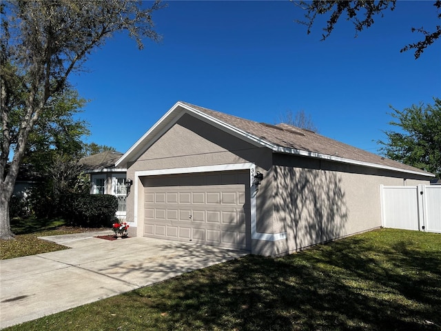 view of side of home featuring fence, concrete driveway, a lawn, stucco siding, and a garage