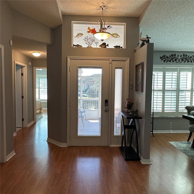 entryway with wood finished floors, baseboards, a chandelier, and a textured ceiling