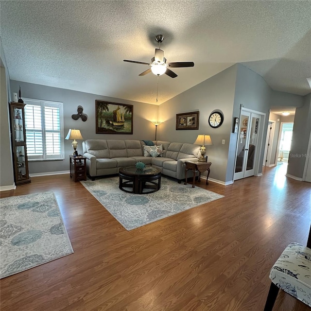 living area with baseboards, lofted ceiling, wood finished floors, a textured ceiling, and a ceiling fan