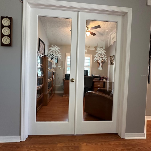 interior space featuring ceiling fan, wood finished floors, baseboards, and a textured ceiling