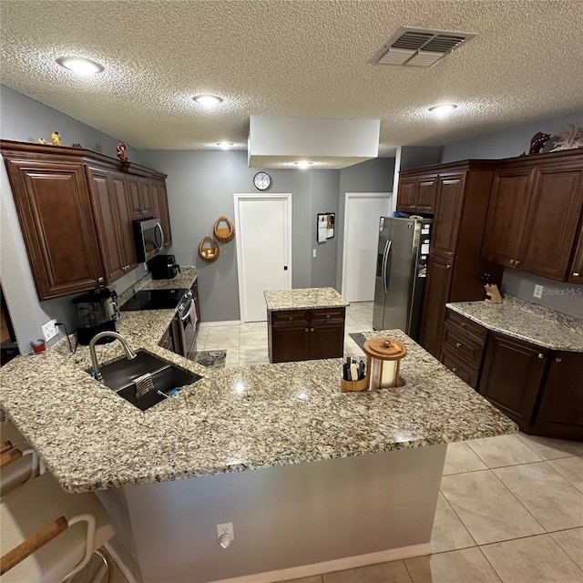 kitchen with visible vents, a sink, a center island, stainless steel appliances, and a peninsula