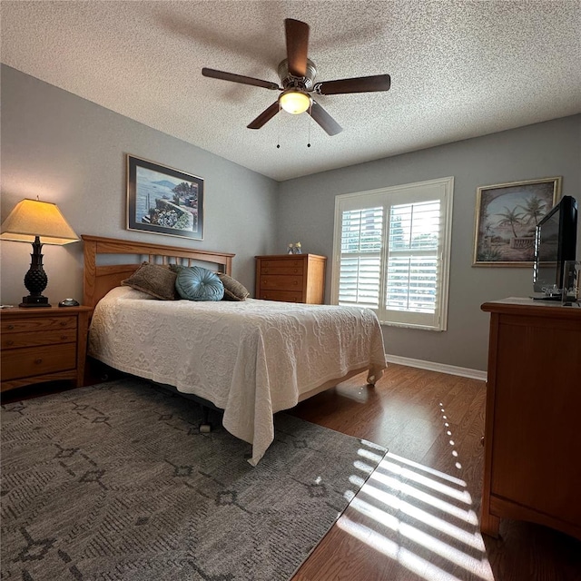 bedroom featuring a ceiling fan, wood finished floors, baseboards, and a textured ceiling