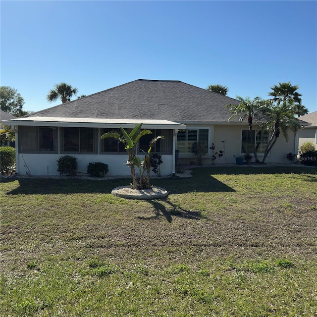 back of house featuring a yard, a shingled roof, and a sunroom