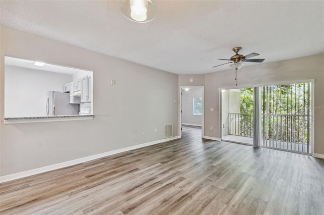 unfurnished living room with baseboards, visible vents, light wood finished floors, and ceiling fan