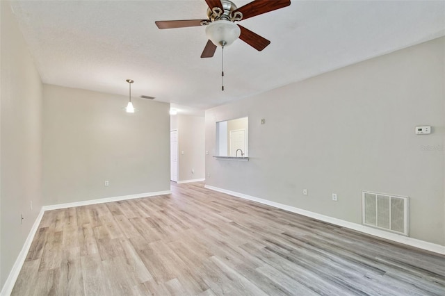 empty room featuring baseboards, visible vents, and light wood finished floors