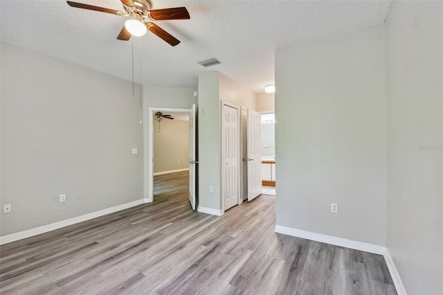 unfurnished bedroom featuring ceiling fan, a textured ceiling, baseboards, and wood finished floors