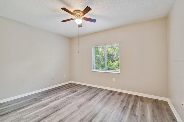 empty room with baseboards, a textured ceiling, wood finished floors, and a ceiling fan