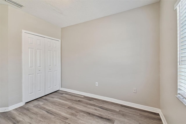 unfurnished bedroom featuring wood finished floors, visible vents, and baseboards