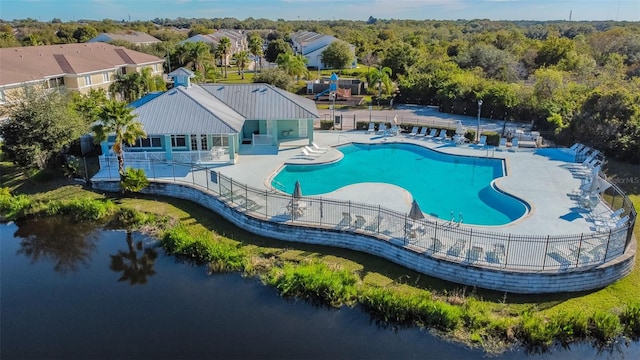 community pool featuring a water view, a patio, and fence