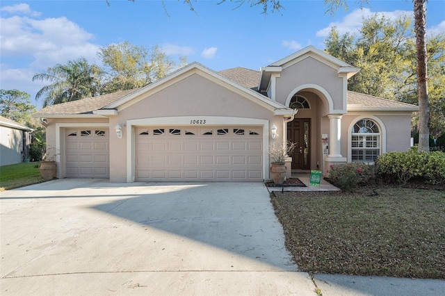 mediterranean / spanish house with stucco siding, concrete driveway, an attached garage, and a shingled roof