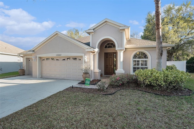 view of front of home featuring a shingled roof, fence, concrete driveway, stucco siding, and a garage