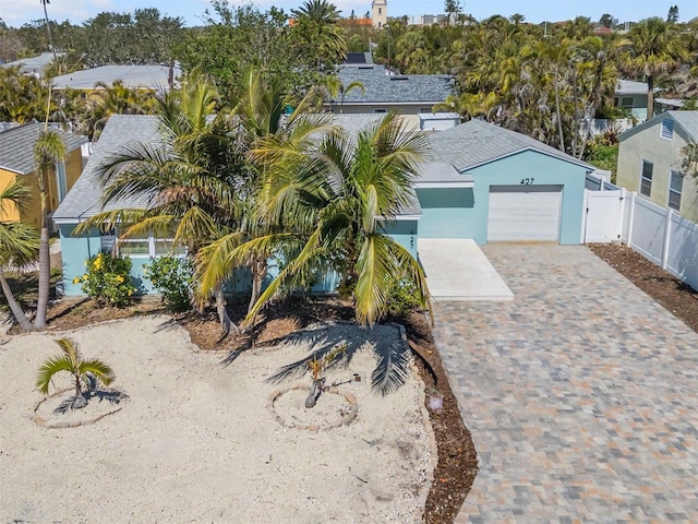 view of front of house featuring stucco siding, decorative driveway, a garage, and fence