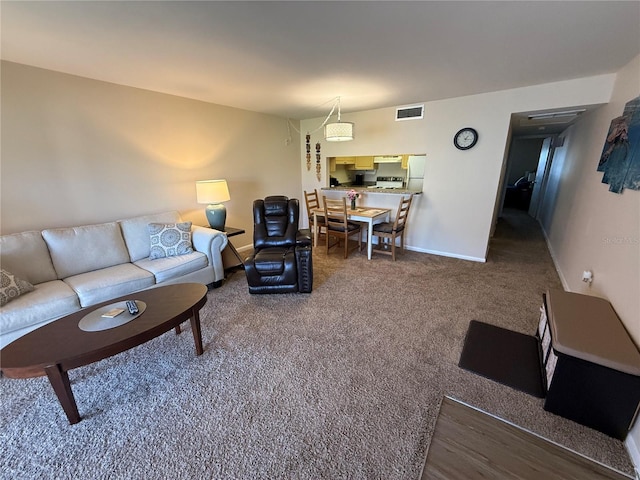 living area with baseboards, visible vents, and carpet floors