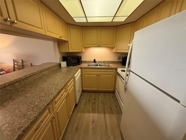 kitchen featuring dark countertops, white appliances, wood finished floors, and a sink