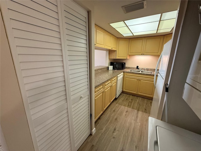 kitchen with light wood finished floors, a sink, visible vents, and white dishwasher