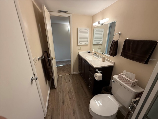 bathroom with vanity, wood finished floors, visible vents, baseboards, and toilet