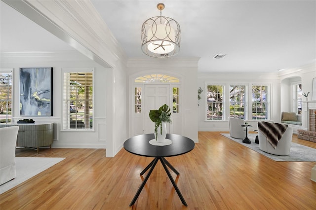 entryway with visible vents, light wood finished floors, plenty of natural light, ornamental molding, and a chandelier