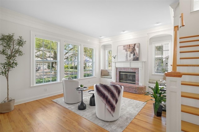 living area featuring baseboards, stairway, ornamental molding, a fireplace, and wood finished floors