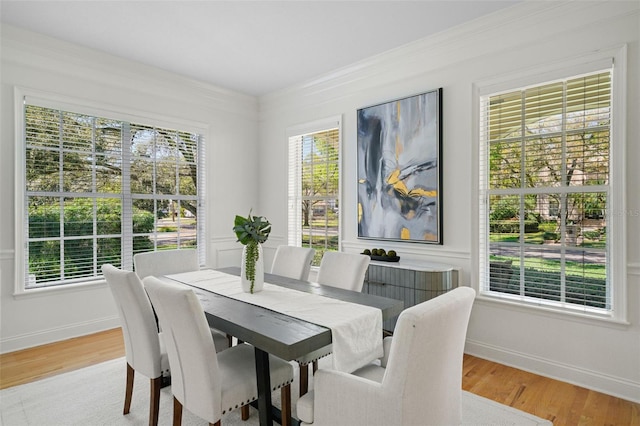 dining area featuring baseboards, light wood-style floors, and ornamental molding