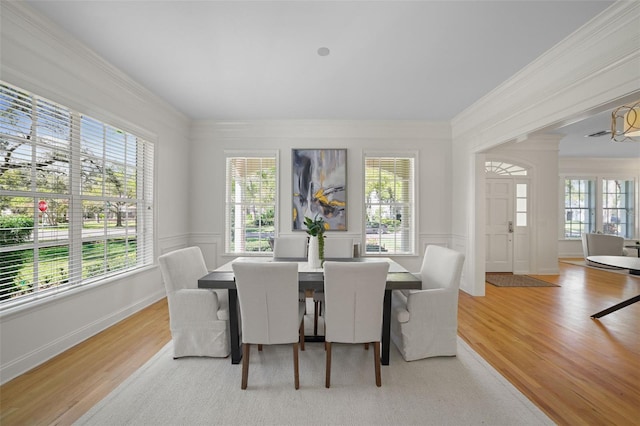 dining area with a decorative wall, crown molding, and light wood-style floors