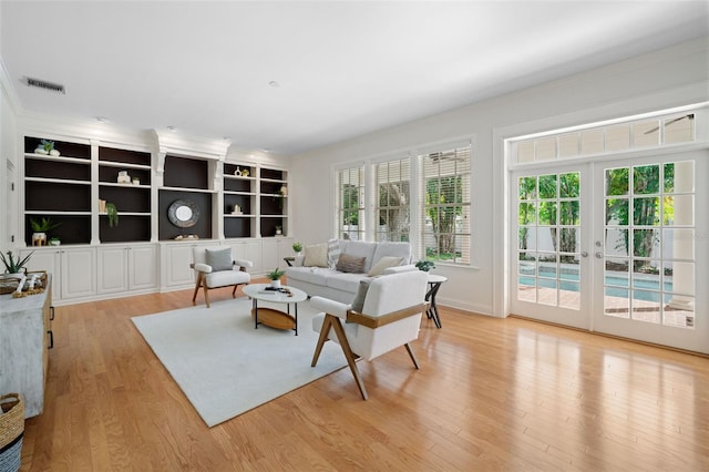 living area with visible vents, french doors, crown molding, and wood finished floors