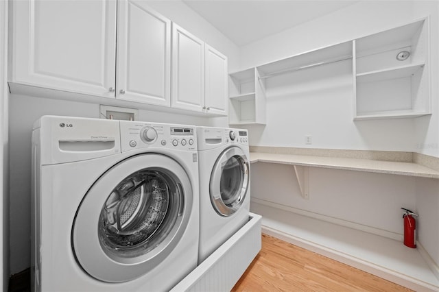 washroom featuring light wood-style floors, cabinet space, and separate washer and dryer