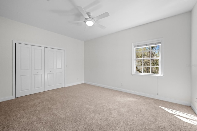 unfurnished bedroom with a closet, carpet flooring, a ceiling fan, and baseboards