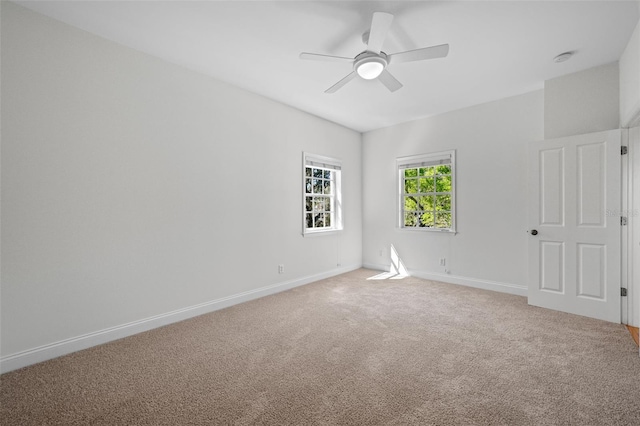 empty room featuring a ceiling fan, light colored carpet, and baseboards