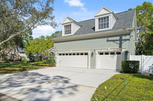 view of front of home with stucco siding, a shingled roof, driveway, and fence