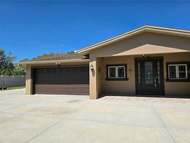 view of front facade with fence, a garage, driveway, and stucco siding