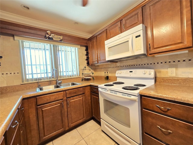 kitchen featuring light tile patterned floors, brown cabinets, white appliances, and a sink