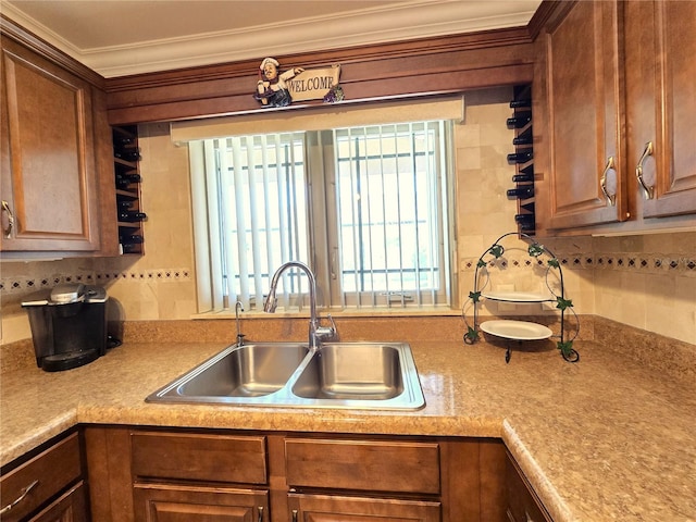 kitchen with brown cabinets, a sink, backsplash, crown molding, and light countertops