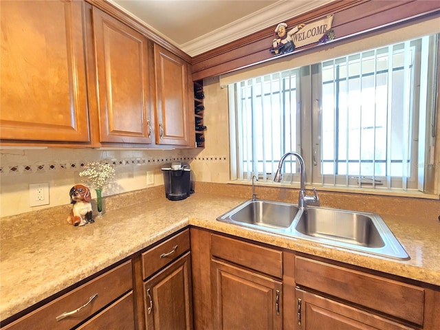 kitchen featuring crown molding, a healthy amount of sunlight, brown cabinetry, and a sink